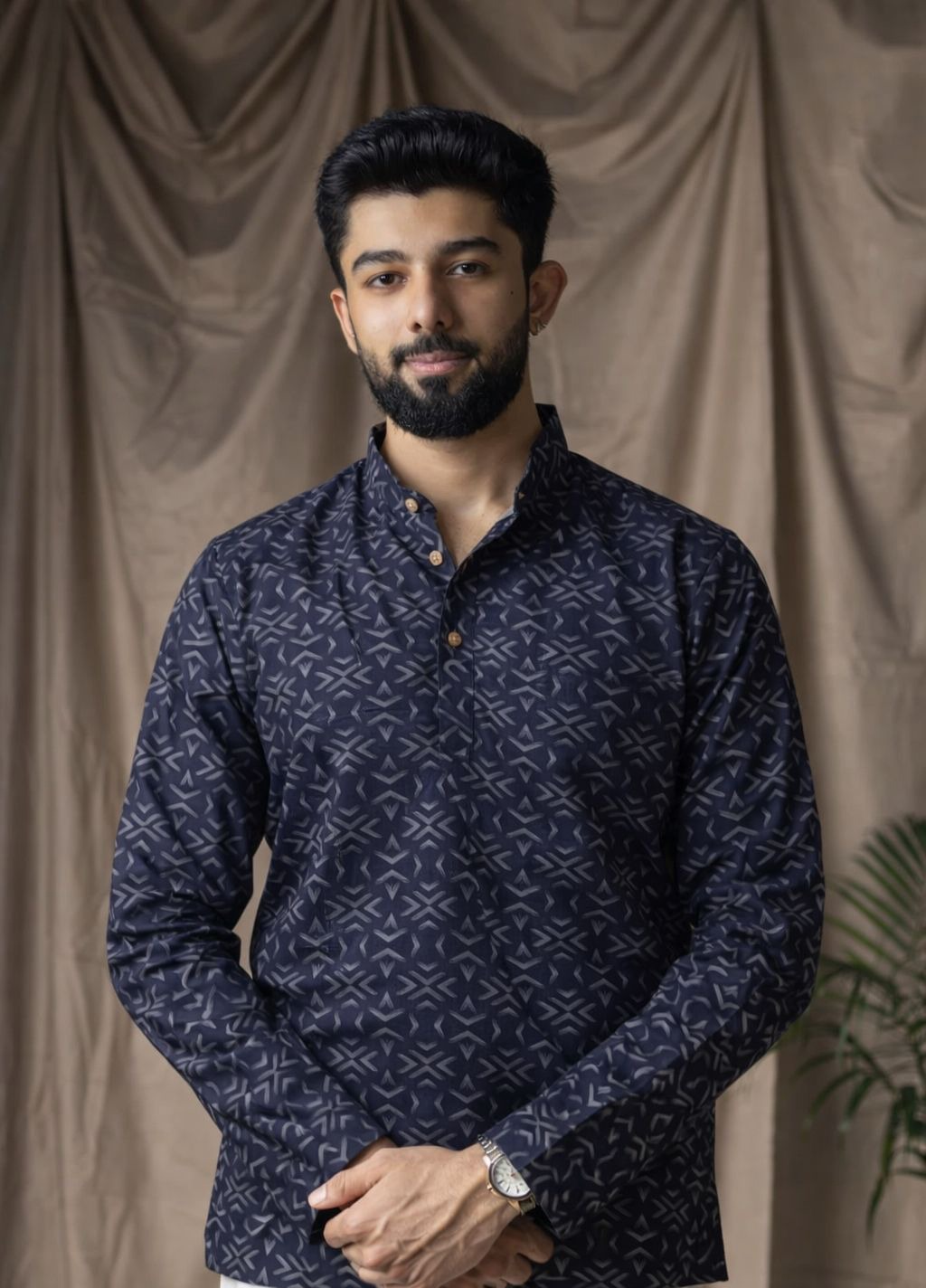 A man wearing a dark navy blue long-sleeve kurta with a white geometric pattern.