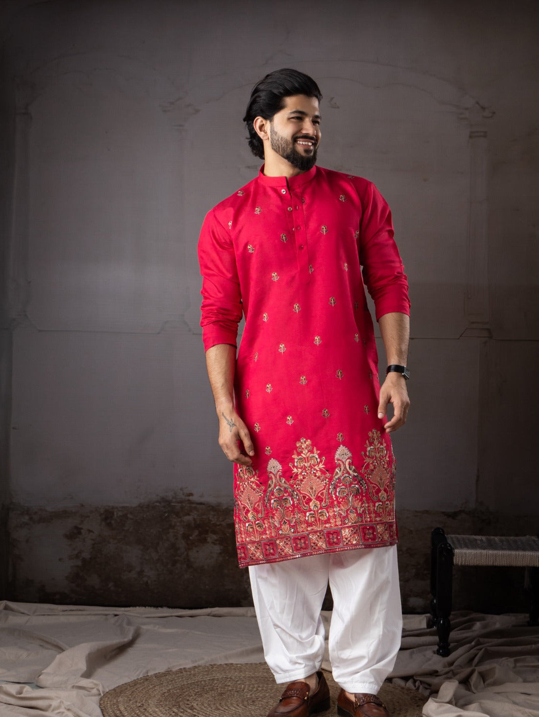 Man wearing a red kurta with white pants against a plain background