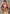 A woman models a traditional Indian outfit featuring a deep maroon embroidered jacket over a beige saree, set against a textured gray wall.